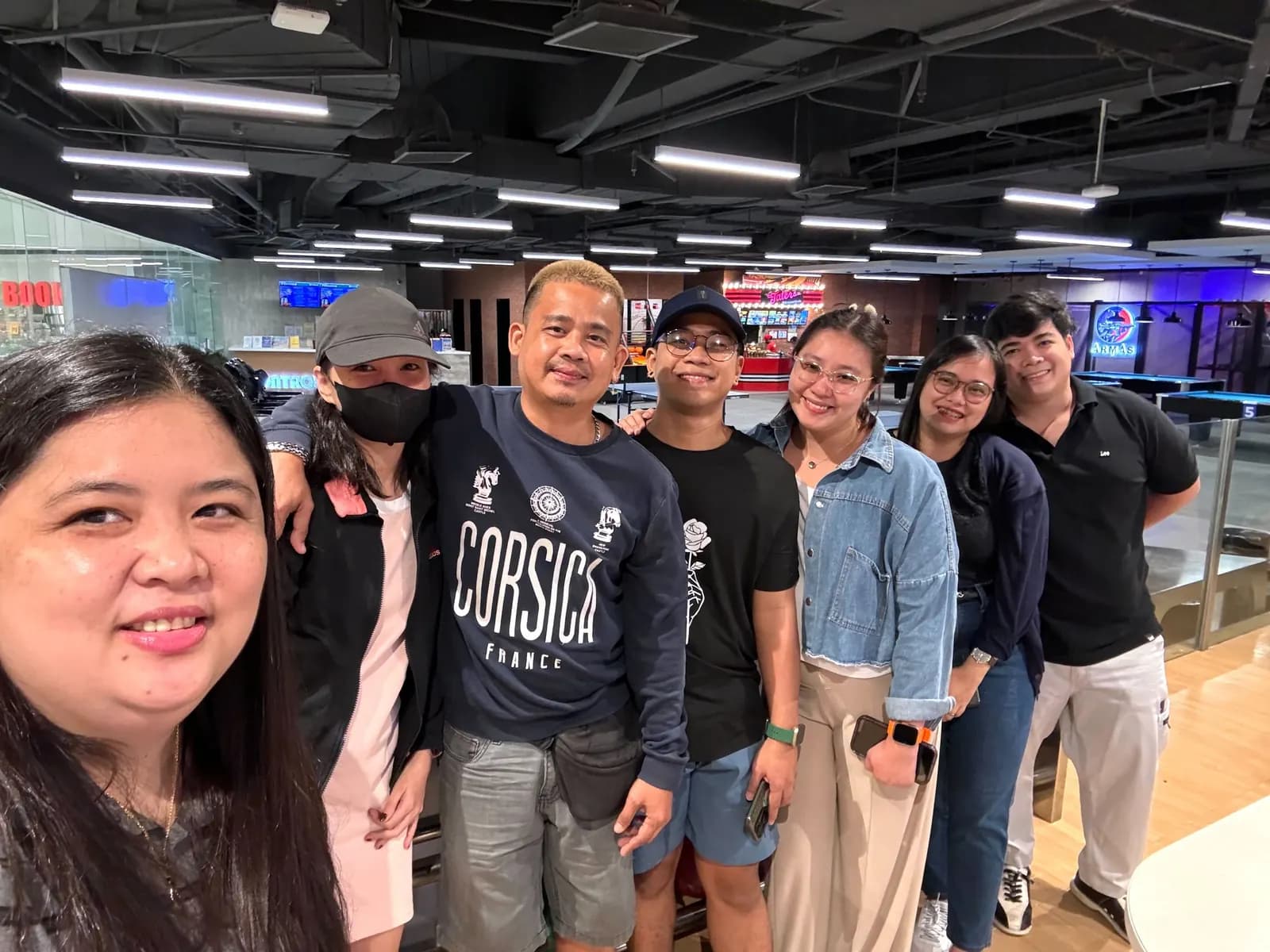Seven BrokerVA teammates standing shoulder to shoulder in front of the bowling lanes