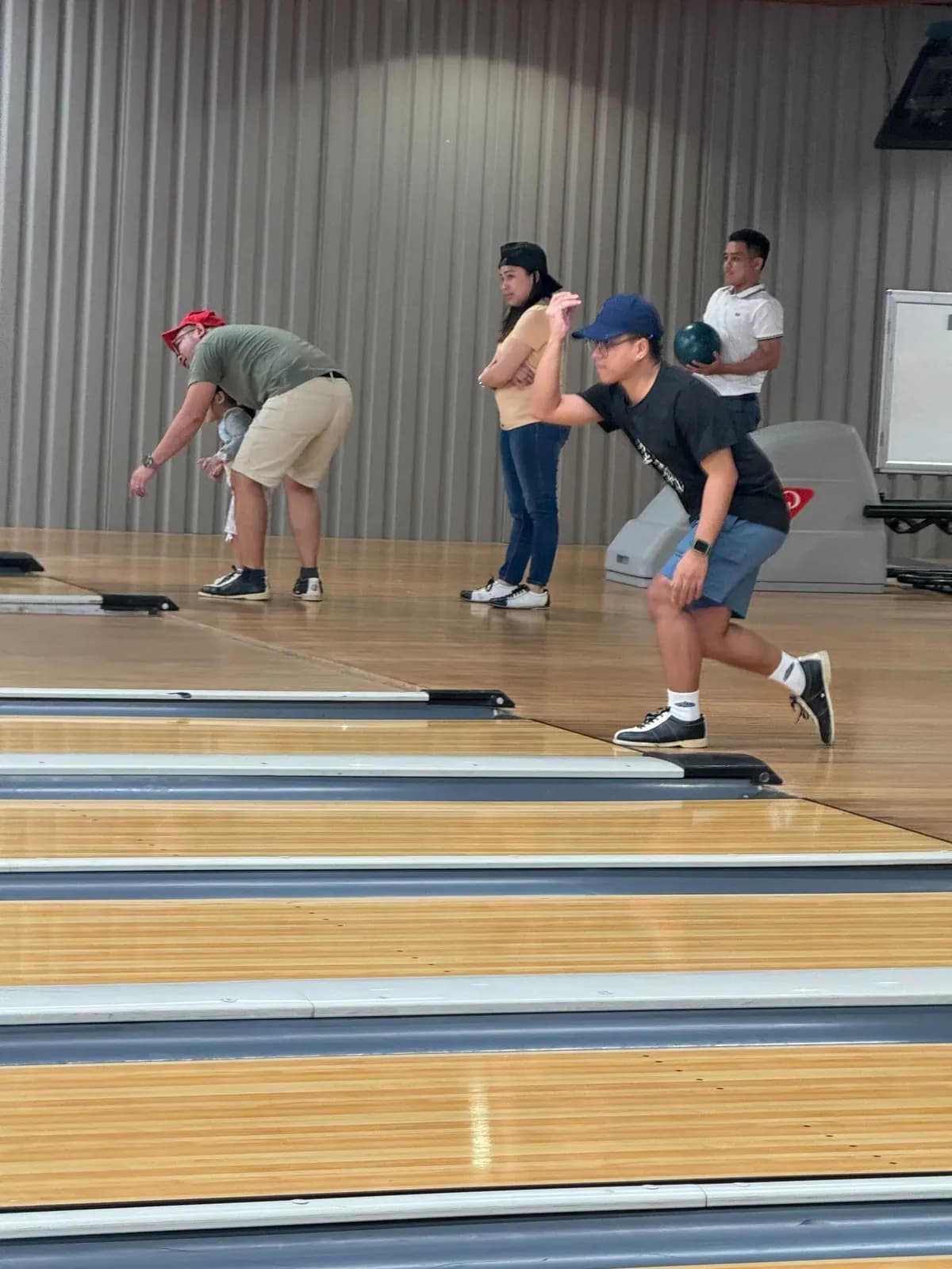 Two teammates mid-throw on adjacent lanes during the BrokerVA bowling outing