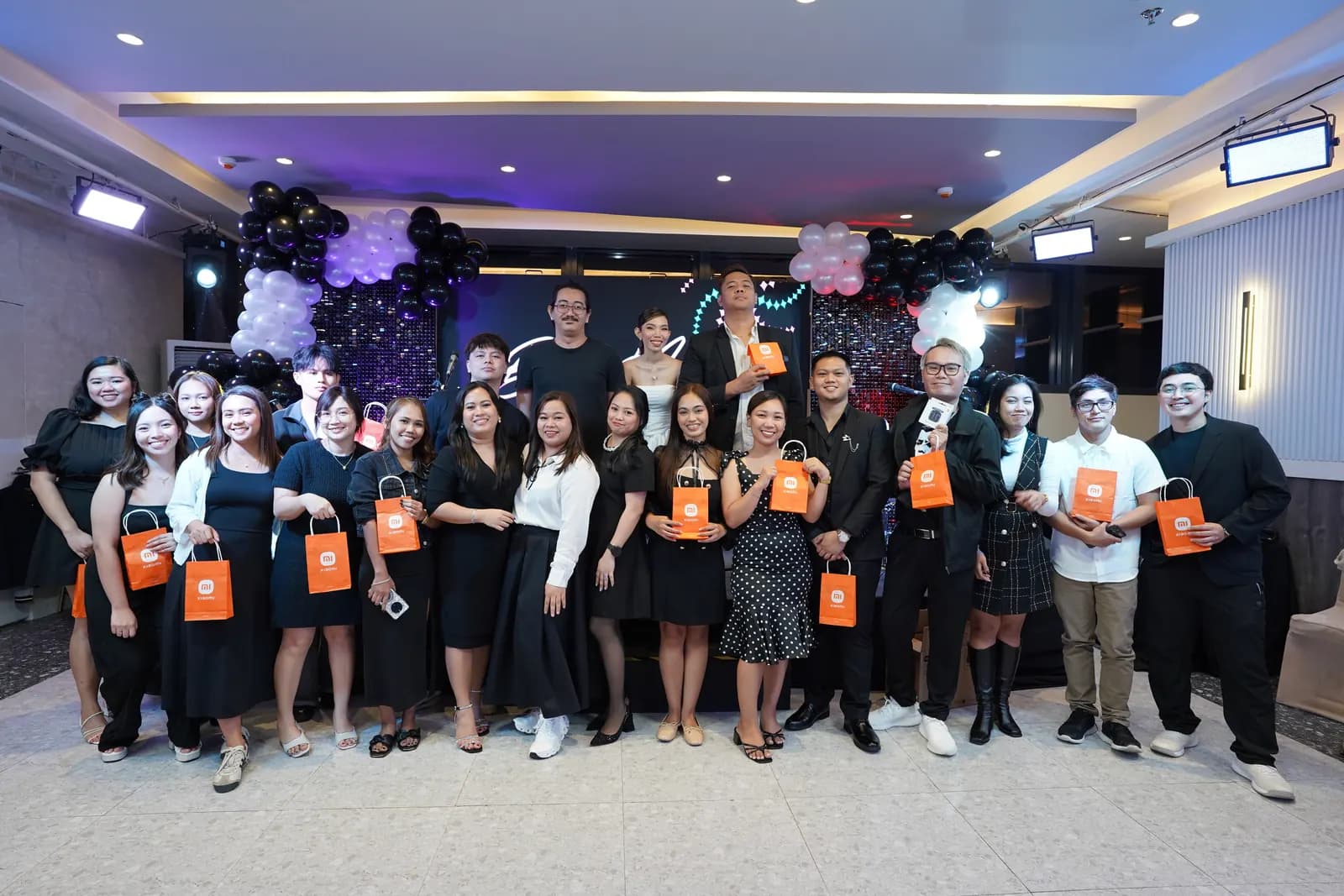 Teammates on stage holding their gift bags at the 2025 year-end party